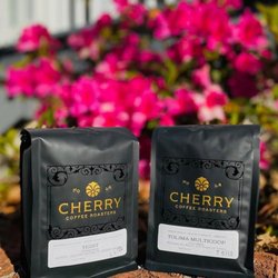 Cherry Coffee Roasters - New Orleans - Two bags of Cherry Coffee Roasters coffee beans in front of flowers