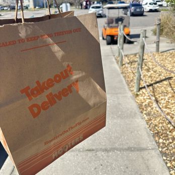 Hooters - a person holding a takeout delivery bag - Sports Bars Near Me - Lakeland, Florida