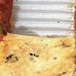 Black soot from dirty pizza oven on bottom of pizza -- deck should be swept between pizza loading.