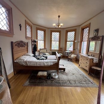Miramont Castle - a bedroom with a bed, dressers, and a chair - Tea Rooms Near Me - Manitou Springs, Colorado Miramont Castle - a bedroom with a bed, dressers, and a chair - Tea Rooms Near Me - Manitou Springs, Colorado