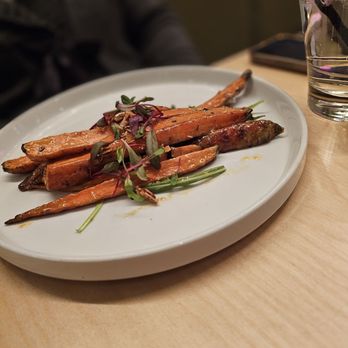 Nafsi - Appetizer: glazed carrots - A white plate holds glazed carrots topped with microgreens, served at a restaurant with a glass of water and a smartphone nearby. - New American Near Me - Chicago, Illinois