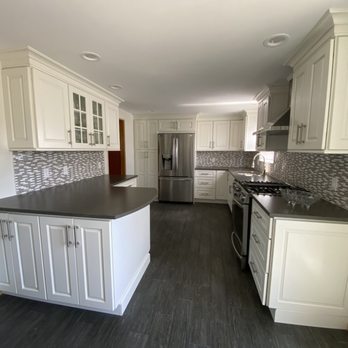 FRM Home Improvements - a kitchen with white cabinets and black countertops - General Contractors Near Me - Coram, New York