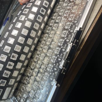 Johnson Computer - The image shows a person lifting the keyboard of a disassembled laptop, revealing the internal circuit board and electronic components underneath. The keyboard appears to be removed for repair or maintenance, with visible dust and debris on the internal parts. The workspace includes tools and a wooden surface, indicating a repair setting. - Data Recovery Near Me - Hayward, California