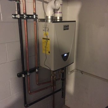 North Wind Heating & Air Conditioning - Wall-mounted tankless water heater installed in a basement mechanical room, connected with copper and PVC piping, showing cle... - Heating & Air Conditioning/HVAC Near Me North Wind Heating & Air Conditioning - Wall-mounted tankless water heater installed in a basement mechanical room, connected with copper and PVC piping, showing cle... - Heating & Air Conditioning/HVAC Near Me