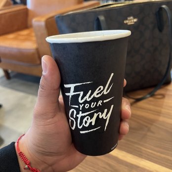 Black Rock Coffee Bar - a hand holding a black paper cup with the words fuel your story written on it - Coffee & Tea Near Me - Pasadena, Texas