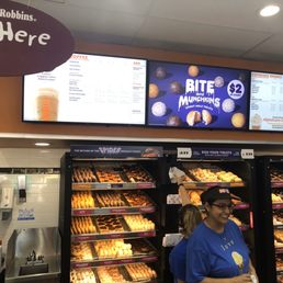  a woman standing in front of a display of donuts