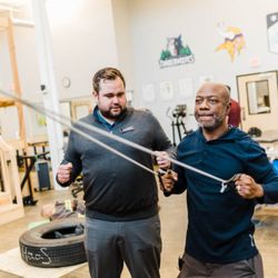 Saunders Therapy Centers - Occupational therapist assisting with stabilizing exercises in St. Paul's industrial rehabilitation gym.