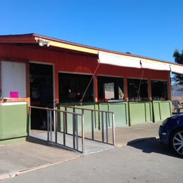 a blue car parked in front of a fruit stand