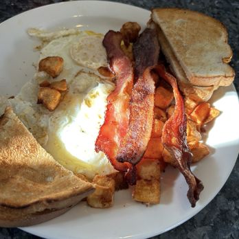 Bernie's Foreside - Classic Breakfast - A breakfast plate featuring fried eggs, crispy bacon, toasted bread, and breakfast potatoes on a white plate. - Breakfast & Brunch Near Me - Falmouth, Maine