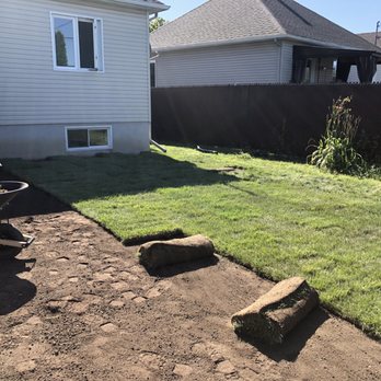 Eminence - a man pushing a wheelbarrow in a backyard - Landscaping Near Me