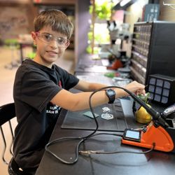 Meta Humans - Member soldering an electronics badge.