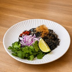 Yum Pla Muek. Sauteed calamari in lemongrass sweet and savory squid ink sauce. Tossed with fresh herbs, chili, and lime juice.