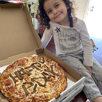 Gridiron Pizza - a little girl sitting in front of a pizza - Chicken Wings Near Me - Adelanto, California