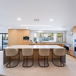 Renovo Remodeling - High-end kitchen remodel featuring custom cabinetry, a large waterfall island, integrated appliances, and a clean, modern design.
