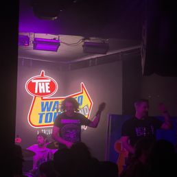 a man on stage in front of a neon sign