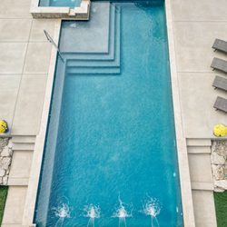 Blue Haven Pools & Spas - A modern rectangular swimming pool features a raised spa, tanning ledge, and sheer descent water features.