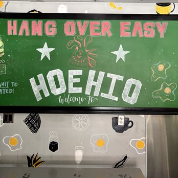 HangOverEasy - A green chalkboard sign with pink, white, and orange lettering and illustrations, welcoming visitors to Hoehio at HangOverEasy in Columbus, OH. - Breakfast & Brunch Near Me - Columbus, Ohio