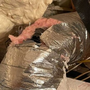 Mission Air Services - Close-up of damaged flexible HVAC ductwork in an attic, showing torn outer foil insulation, exposed pink fiberglass, crushed ... - Heating & Air Conditioning/HVAC Near Me Mission Air Services - Close-up of damaged flexible HVAC ductwork in an attic, showing torn outer foil insulation, exposed pink fiberglass, crushed ... - Heating & Air Conditioning/HVAC Near Me