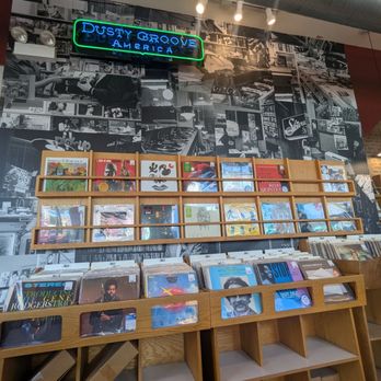 Dusty Groove - Inside - Inside Dusty Groove, a Chicago record store, vinyl records and CDs are arranged on wooden shelves against a black-and-white photo collage wall. - Music & DVDs Near Me - Chicago, Illinois