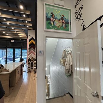 Frame Chicago - The image shows the interior of a retail space with a staircase leading down, coat hooks with jackets, and framed artwork on the wall. - Framing Near Me - Chicago, Illinois