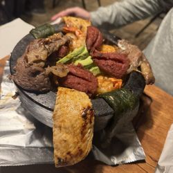 The Art Of Flavors - Molcajete -steak, chicken, shrimp, and sausage with grilled peppers, onions, Mexican cheese, and Ranchero sauce.... enough for 2-4 people!