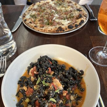Fiorella -Polk - Octopus squid ink pasta in front, Salsiccia Pie in back with Aperol spritz - Pizza Near Me - San Francisco, California Fiorella -Polk - Octopus squid ink pasta in front, Salsiccia Pie in back with Aperol spritz - Pizza Near Me - San Francisco, California
