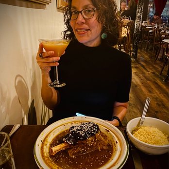 Barbès Restaurant - a woman sitting at a table with a plate of food and a glass of wine - French Near Me - Hoboken, New Jersey Barbès Restaurant - a woman sitting at a table with a plate of food and a glass of wine - French Near Me - Hoboken, New Jersey