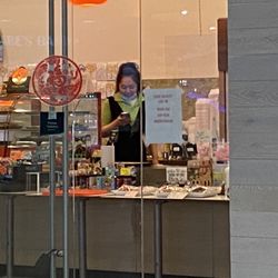 Garden Bakery - Employee with her mask fully down in front of product, so she can talk on her phone