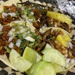 On the left, chicharrón tacos and to the right, al pastor tacos with pineapple.