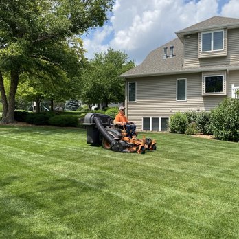 McKay HP - a man mowing the grass in front of a house - Landscaping Near Me - Aurora, Nebraska