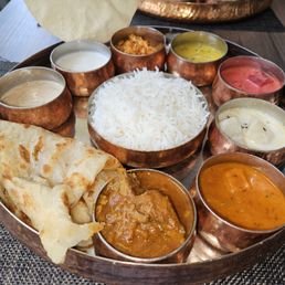 a variety of indian food on a copper platter