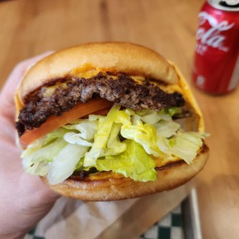 Burger Crush - a hand holding a hamburger with lettuce and tomato - Burgers Near Me - Vancouver, British Columbia