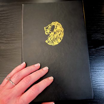 Doar Bros. - a hand holding a book with a lion on it - Cocktail Bars Near Me - Charleston, South Carolina Doar Bros. - a hand holding a book with a lion on it - Cocktail Bars Near Me - Charleston, South Carolina