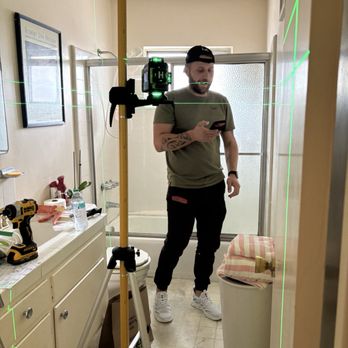 Egor Handyman - Egor using his laser level to project proper lines on bathroom wall to install double bath towel bar. - Handyman Near Me Egor Handyman - Egor using his laser level to project proper lines on bathroom wall to install double bath towel bar. - Handyman Near Me