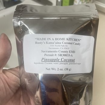 Rusty's Kama'aina Coconut Candy - a hand holding a bag of candy - Specialty Food Near Me