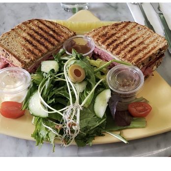 Raintree Bakery Coffeehouse - Reuben Panini Sandwich with green salad and ginger sesame dressing on the side. - Bakeries Near Me - Honolulu, Hawaii Raintree Bakery Coffeehouse - Reuben Panini Sandwich with green salad and ginger sesame dressing on the side. - Bakeries Near Me - Honolulu, Hawaii