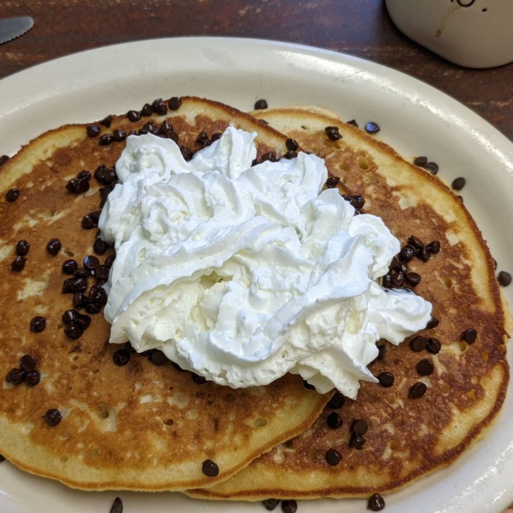 a plate of pancakes with whipped cream and chocolate chips a plate of pancakes with whipped cream and chocolate chips