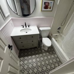 Pro Handy Services - Full bathroom renovation: new tile, vanity and toilet installed, fresh paint, wall panels added, new baseboards. Clean modern look.