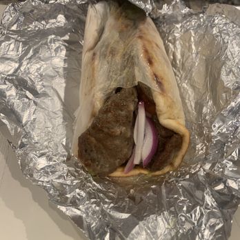 Cedar Tree - Gyro Pita - A gyro wrap with meat, onions, and sauce partially unwrapped from aluminum foil, showing the ingredients inside. - Mediterranean Near Me - River Vale, New Jersey