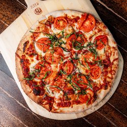 Margherita pizza with house red sauce, Wisconsin mozzarella, Roma tomatoes, fresh basil, and fresh dough.