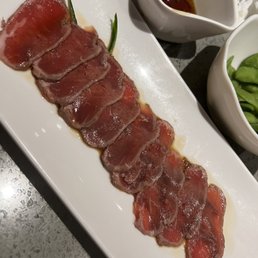 a plate of sliced meat and a bowl of green beans a plate of sliced meat and a bowl of green beans