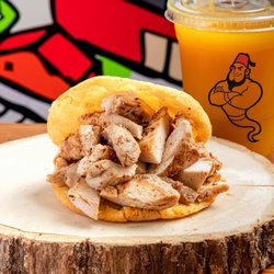 El Genio del Shawarma - Juicy, seasoned grilled chicken stuffed inside a warm, golden arepa. Served with a refreshing drink. A true Venezuelan classic!