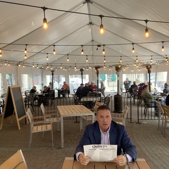 Quincy’s Potomac Bar & Grille - a man sitting at a table with a menu - Salad Near Me - Potomac, Maryland Quincy’s Potomac Bar & Grille - a man sitting at a table with a menu - Salad Near Me - Potomac, Maryland