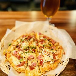 Kushala Sip Lounge & Cafe Bar - Polones Pitza Brava - pita, brava sauce, mozzarella, parmesan, feta, kielbasa, serrano ham, shitake mushroom, microgreens.
