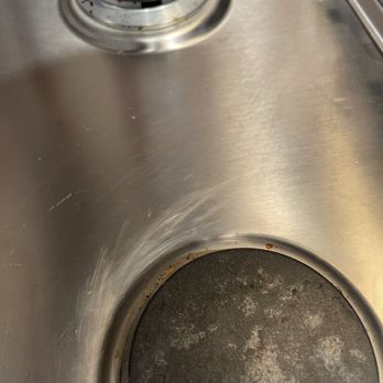 Sandia Green Clean - Scratches on cooktop - A stainless steel kitchen stovetop with two burners, one with visible stains and grime, indicating it needs cleaning. - Home Cleaning Near Me - Albuquerque, New Mexico