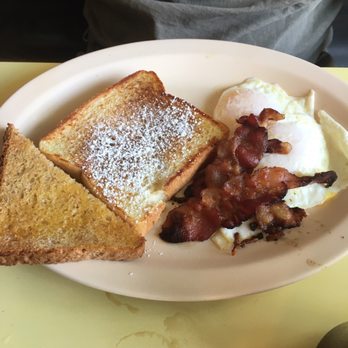 Poor Richards Cafe - a plate of breakfast food - A breakfast plate featuring two slices of toasted bread, eggs, and bacon, served on a white oval plate at Poor Richards Cafe in Kalamazoo, MI. - Cafes Near Me - Kalamazoo, Michigan