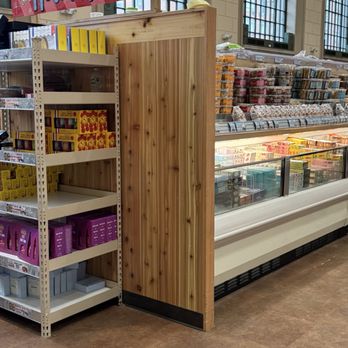 Trader Joe's - A store interior features a wooden display shelf with holiday gift boxes and a sign promoting holiday gifts, with refrigerated items visible in the background. - Grocery Near Me - Brooklyn, New York