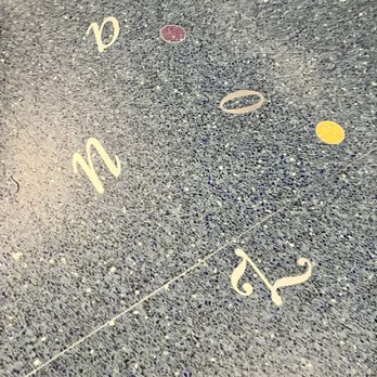 PHX Sky Train - The image shows a textured gray ground surface with painted numbers and colored dots. The numbers are in a stylized font, and the dots are yellow and purple. The surface appears to be a floor, possibly in a public or commercial space, with a visible seam running across the image. - Trains Near Me - Phoenix, Arizona