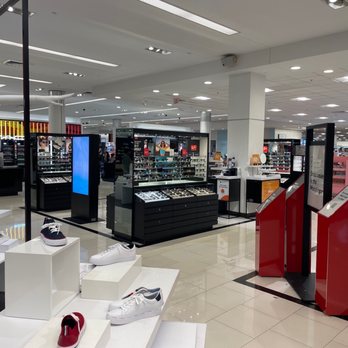 Macy's - Macys - The image shows a section of Macy's department store with various shoes displayed on white platforms and black display cases. The store interior features bright lighting, white tiled floors, and a spacious layout. Checkout kiosks with digital screens are positioned near the entrance of this section. The background includes additional retail displays and signage, indicating a large retail environment focused on footwear and accessories. - Department Stores Near Me - Columbus, Ohio