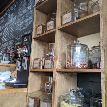Caffe Cafe - Wooden shelves hold glass jars filled with herbs, spices, and dried ingredients in a coffee shop setting. - Cafes Near Me - Brooklyn, New York